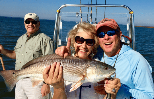 A couple pose with a fish aboard a boat
