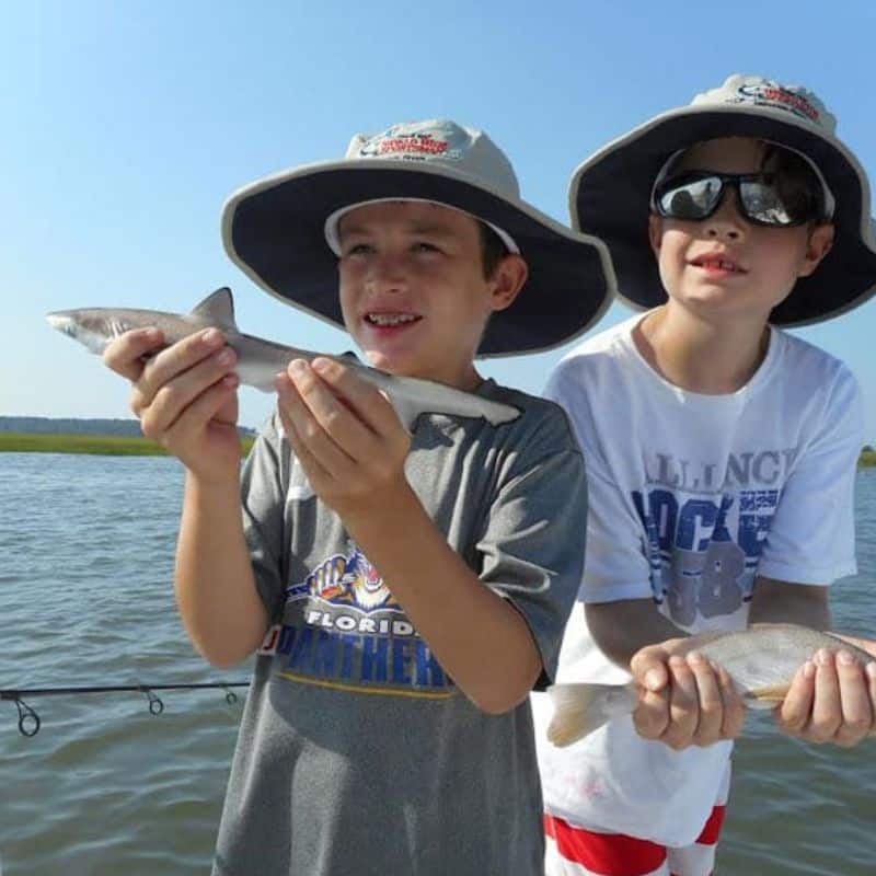 Kids holding small fish on Cast Away fishing and boating charter