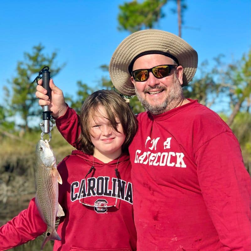 Father and child smiling with catch on Cast Away fishing and boating charters in the Lowcountry