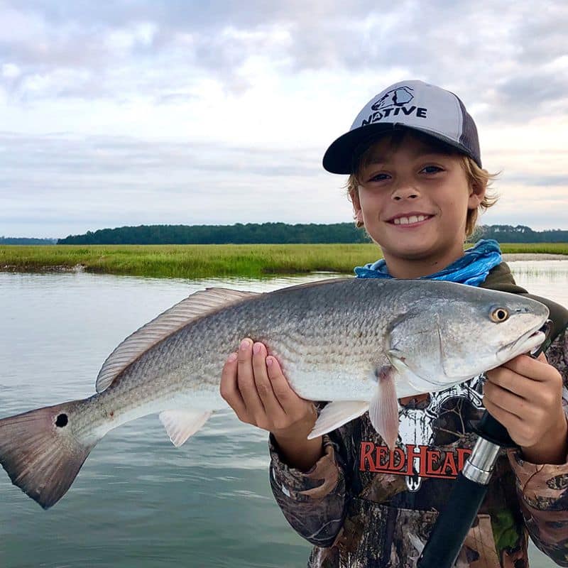 Boy holding fish on Cast Away fishing and boating charters near St. Helena Island