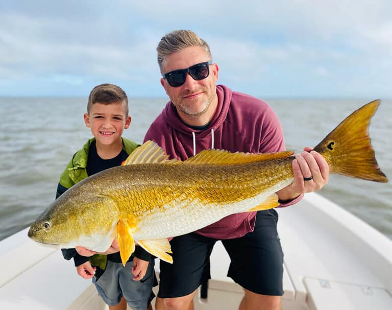 Father and son holding redfish on Cast Away fishing and boating charters in the Sea Islands