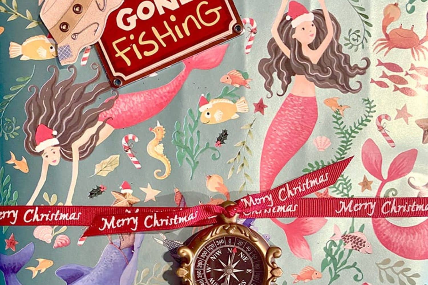 A Christmas gift folio with mermaids in Santa hats and a gone fishing sticker